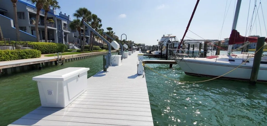 A marina dock with dock boxes and shore power pedestals and boats on the water.