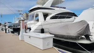 Fiberglass dock box on a marina slip with a power pedestal and boat in background.