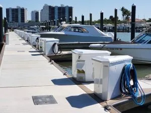 Dockside view of a luxury marina with clean dock boxes and skyscrapers in the distance.