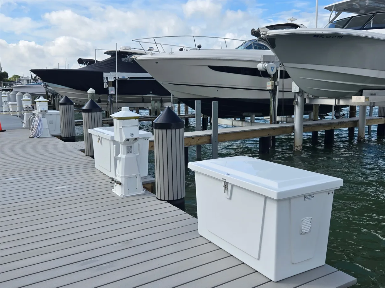 View of a luxury marina with dockside storage boxes and power pedestals. Boats on the water in the background.